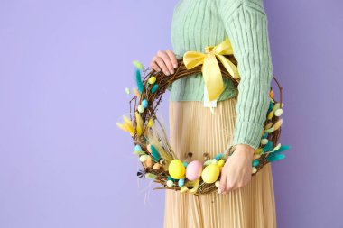 Renkli arkaplanda güzel Paskalya çelengi olan bir kadın.