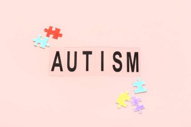Pembe arkaplanda bulmaca parçaları olan kelime AUTISM
