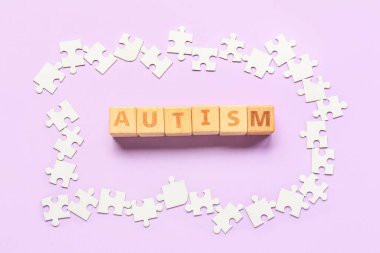 Leylak arka planında kelime AUTISM ve yapboz parçaları içeren küplerName