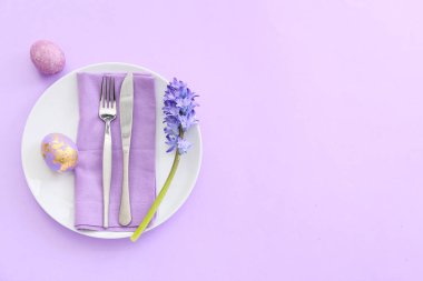 Paskalya yumurtaları ve leylak arkaplanda çiçeklerle güzel bir masa.