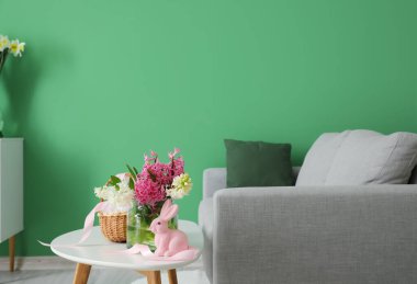 Çiçekli vazo ve oturma odasındaki kanepenin yanındaki paskalya tavşanı.