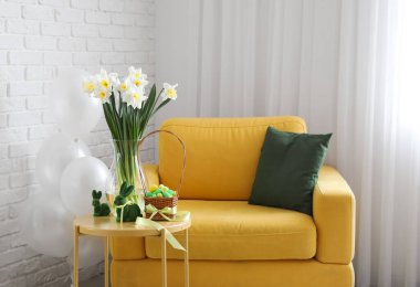 Çiçekli vazo, Paskalya tavşanları ve yumurtalar odanın yanındaki koltuğun yanında.