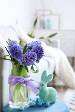 Sümbül çiçekli vazo, Paskalya yumurtası ve tavşanı masada.