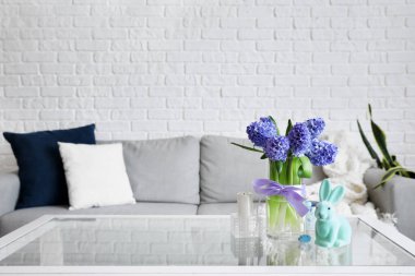 Paskalya tavşanı, mum ve vazo, oturma odasındaki masada sümbül çiçekleri.