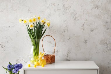 Nergisli vazo çiçekler, Paskalya yumurtaları ve ışık duvarının yanındaki çekmecelerde tavşancık.