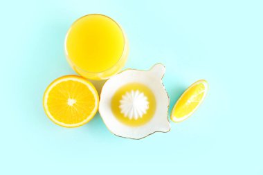 Seramik sıkacağı, mavi arka planda bir bardak meyve suyu ve portakal suyu.