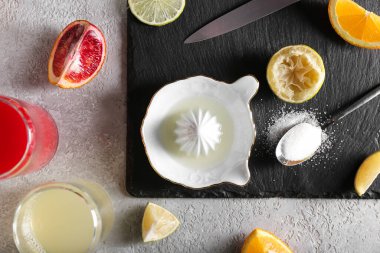 Gri arkaplanda seramik meyve sıkacağı, meyve suyu, şeker ve turunçgiller