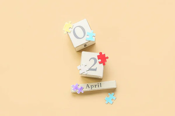 キューブカレンダー日付の世界自閉症意識の日とベージュの背景にパズルピース — ストック写真
