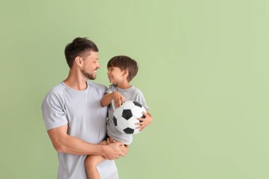 Yeşil arka planda küçük çocuğu ve topu olan erkek antrenör.