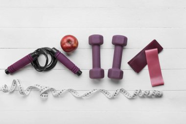 Hafif ahşap arka planda şık spor aletleri ve elma