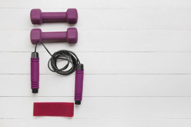 Şık halterler, elastik bant ve hafif ahşap arka planda ip atlama.