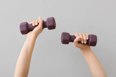 Hafif arka planda şık bir dambılı olan kadın elleri