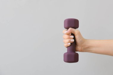 Hafif arka planda şık halterli bir kadın el.