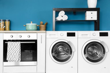 Modern çamaşır makinesi ve fırını olan şık bir mutfak.