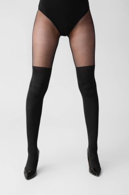 Açık arkaplanda siyah taytlı güzel bir kadın.