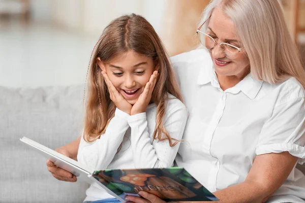 Έκπληκτο Κοριτσάκι Γιαγιά Της Διαβάζει Βιβλίο Στον Καναπέ Στο Σπίτι — Φωτογραφία Αρχείου