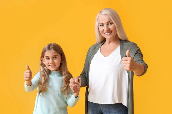 Dojrzała Kobieta Swoją Wnuczką Pokazuje Kciuki Góry Żółtym Tle — Zdjęcie stockowe
