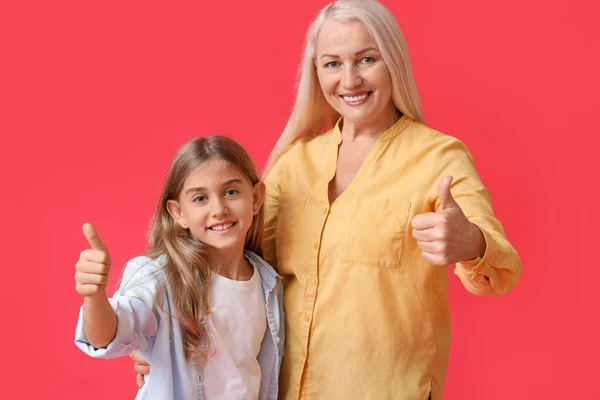 女の子と彼女の祖母ショー親指アップ上の赤い背景 — ストック写真