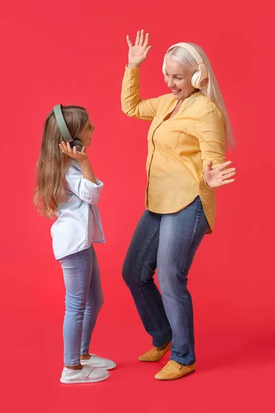 Klein Meisje Haar Oma Koptelefoon Dansen Rode Achtergrond — Stockfoto