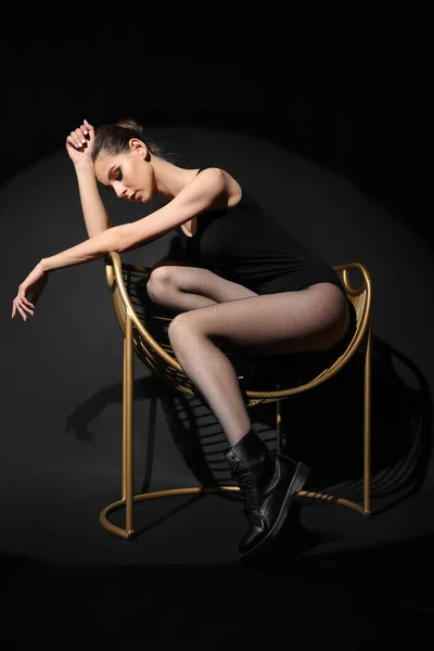 ファッショナブルな若いです女性で黒タイツで座っていますアームチェア上の暗い背景 — ストック写真