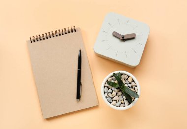 Renk arkaplanında ev bitkisi ve defter olan yeni çalar saat