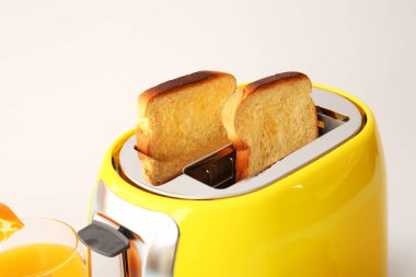 Ekmek dilimli modern tost makinesi ve arka planda bir bardak meyve suyu, yakın plan.