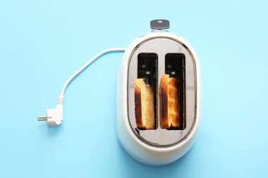 Mavi arka planda ekmek dilimleri olan modern bir tost makinesi.