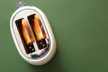 Yeşil zemin üzerinde ekmek dilimleri olan modern ekmek kızartma makinesi