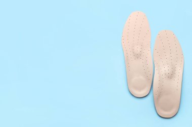 Mavi arka planda bir çift deri ortopedik taban.