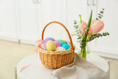 Paskalya yumurtaları ve çiçeklerle dolu hediye sepeti.