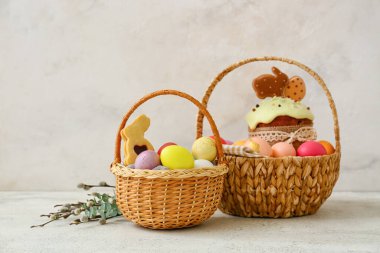 Renkli Paskalya yumurtaları ve açık arkaplanda pasta olan hediye sepetleri