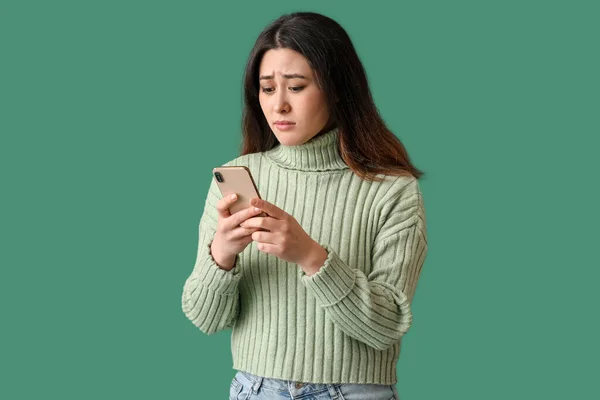 Yeşil Arka Planda Cep Telefonu Olan Üzgün Genç Asyalı Kadın — Stok fotoğraf
