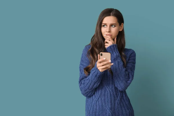 Krásná Přemýšlivá Mladá Žena Mobilním Telefonem Modrém Pozadí — Stock fotografie