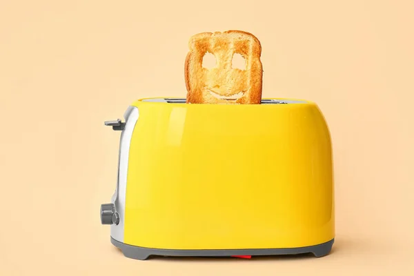 米色背景的烤面包机里有块有趣的面包 — 图库照片
