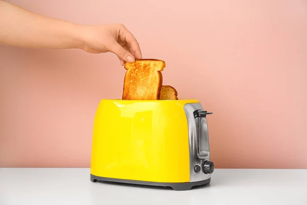 Frau Nimmt Brotscheibe Aus Toaster Auf Beigem Hintergrund — Stockfoto