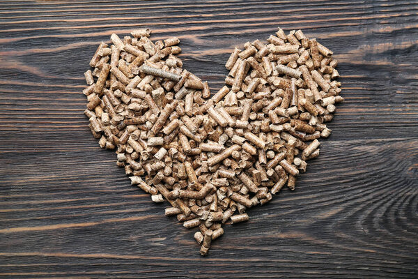 Heart made of wood pellets on wooden background