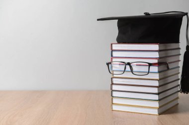 Masada kitap, gözlük ve mezuniyet şapkası olan yaratıcı kompozisyon