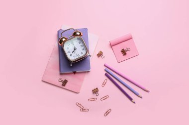 Pembe arka planda kırtasiye ve alarm saati