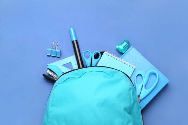 Mavi arkaplanda kırtasiye malzemesi olan sırt çantası, yakın plan