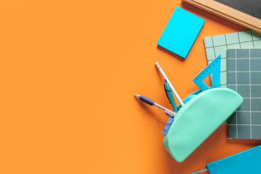 Renk arkaplanı üzerine not defterleri ve kırtasiyeli kalem kutusu