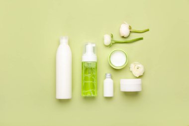 Yeşil arka planda kozmetik ürünleri ve ranunculus çiçekleriyle kompozisyon