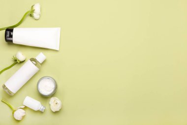 Yeşil arka planda kozmetik ürünleri ve ranunculus çiçekleriyle kompozisyon