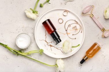 Hafif arkaplanda kozmetik ürünleri, aksesuarlar ve ranunculus çiçekleriyle kompozisyon