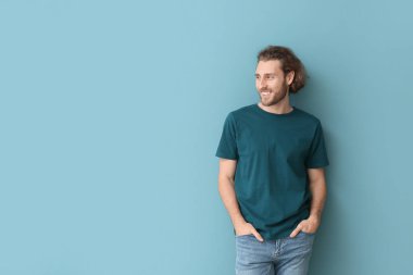 Mavi arka planda şık tişörtlü yakışıklı genç adam.