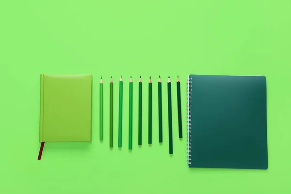 绿色背景的笔记本和彩色铅笔 — 图库照片
