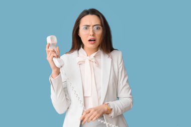 Stresli genç sekreterin portresi mavi arka planda telefonla konuşuyor