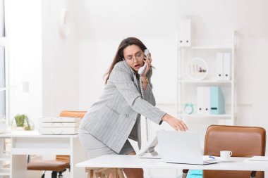 Ofiste telefonla konuşan meşgul genç sekreter.
