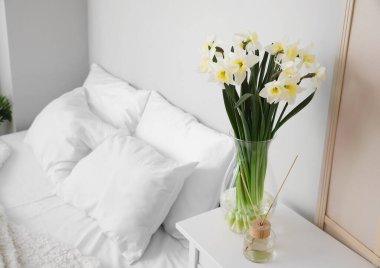 Nergisli vazo ve sazlık ayırıcı açık yatak odasındaki masada.