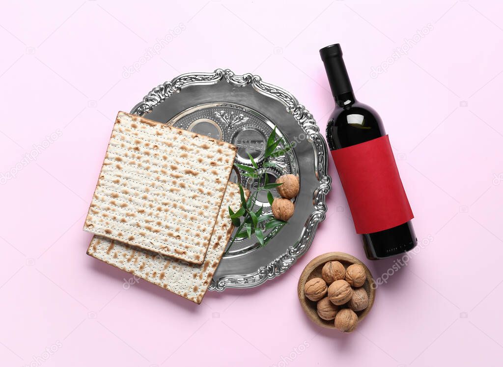 Passover Seder plate, flatbread matza, walnuts and wine on pink background