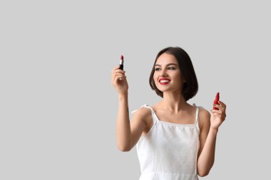 Güzel, gülümseyen bir kadın elinde kırmızı rujla arka planda